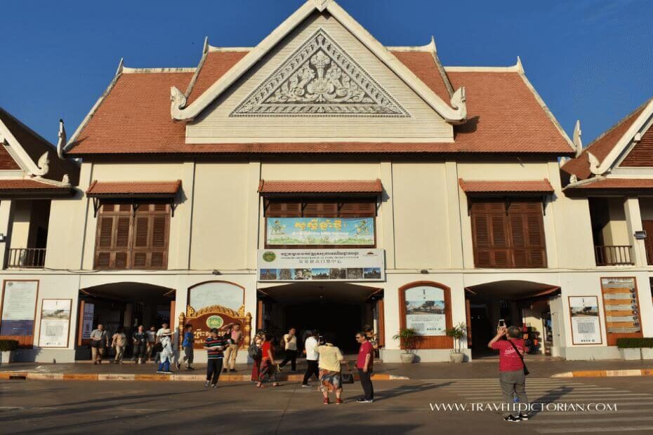 A two story Khmer building with people in front